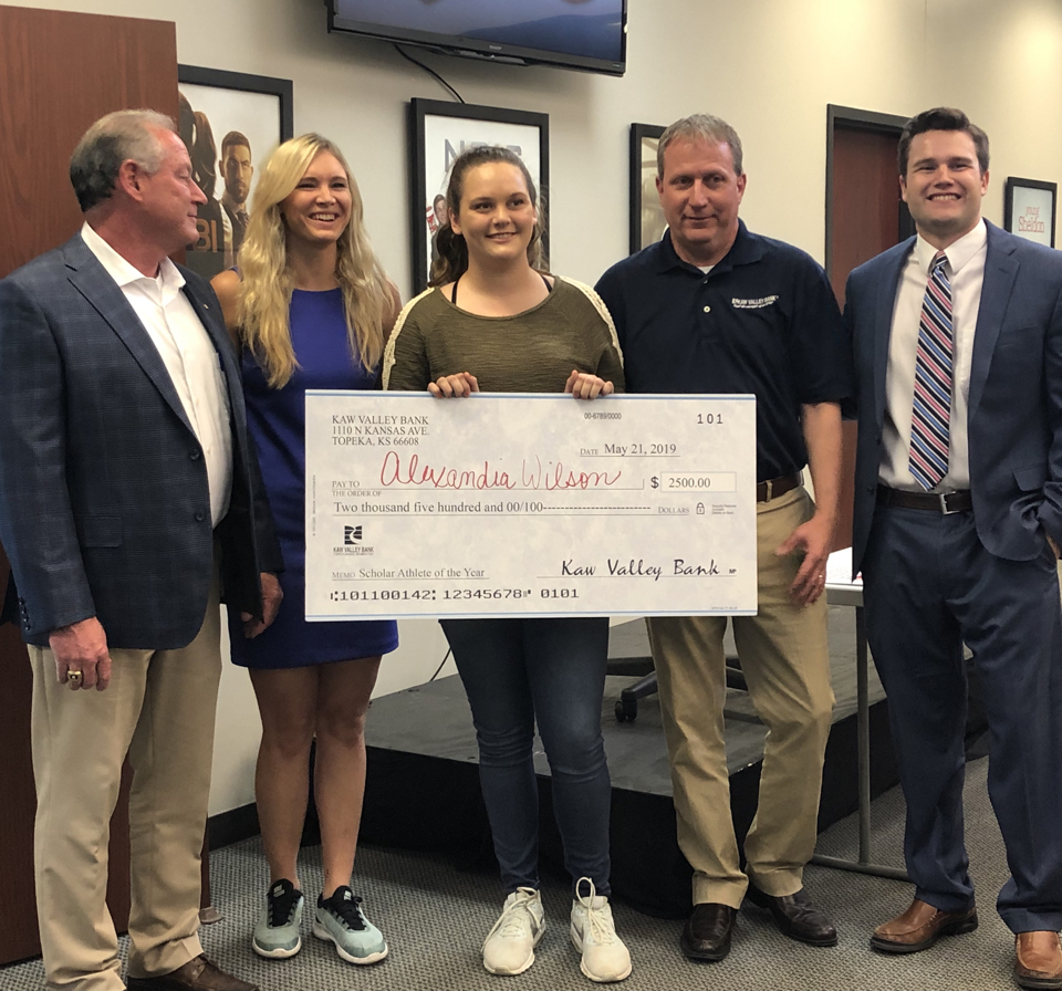 Picture of scholar athlete holding a large check.